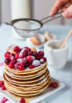 Pancake with cranberries, raspberries and powdered sugar, hands
