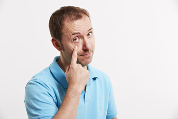 Mann zieht mit dem Finger den Augenlid runter