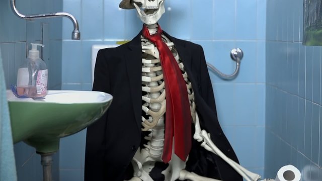 skeleton in business clothes sitting on the toilet