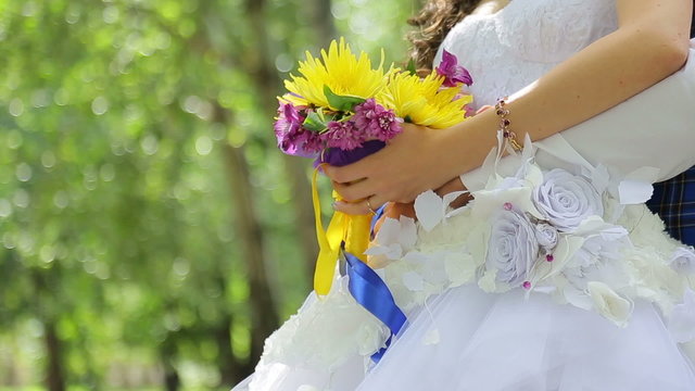 The bride holds a wedding bouquet, groom hugging her waist