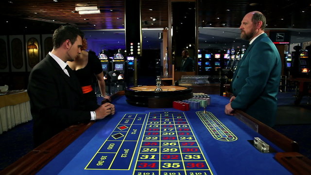 Young and attractive woman whispering to a man while he is about to bet at roulette in casino