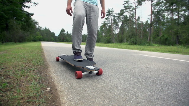Longboarder stop and pick up skate close up slow motion
