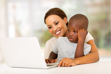 young african woman using laptop with her son