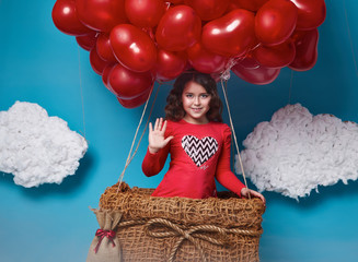 Small cute girl flying on red heart balloons Valentines day