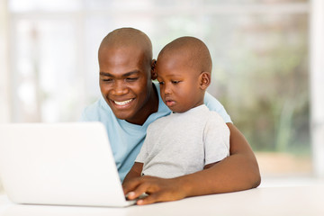young african man using laptop with his son