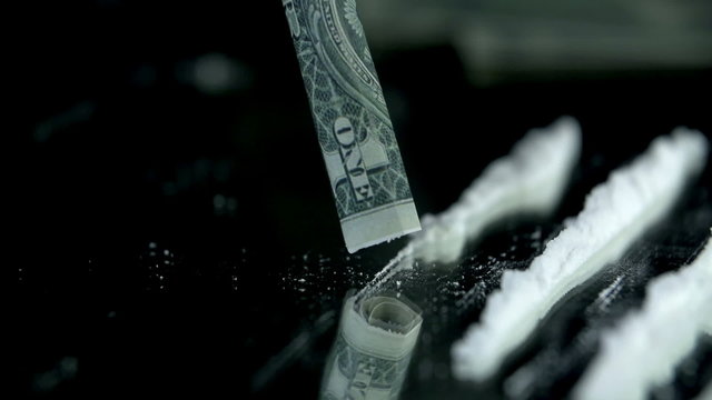 Sniffing the cocaine lines with a dollar bill in slow motion