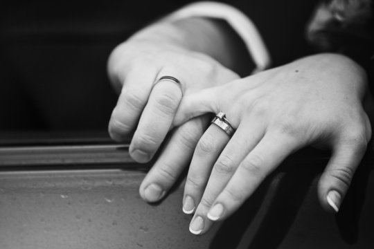 Close up snapshot of a husband lovingly holding his wife's hand.