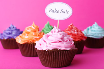 Delicious cupcakes with inscription on color background