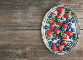 Fototapeta na wymiar Fresh strawberry and blueberry mix on a metal dish (tray) over a