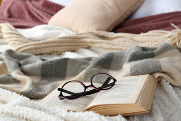 Book and glasses on bed close-up