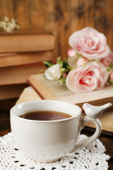 Fototapeta na wymiar Cup of tea with books and flowers on wooden background