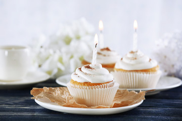 Delicious birthday cupcakes on table on light background