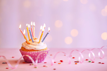 Delicious birthday cupcake on table on light background