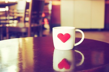 vintage color tone of  cup of coffee with red heart on the table