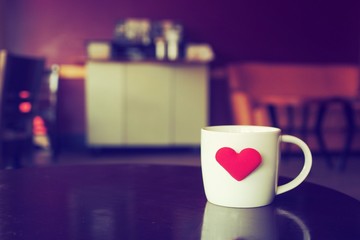 vintage color tone of  cup of coffee with red heart on the table