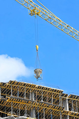 Crane lifting concrete mixer container against blue sky
