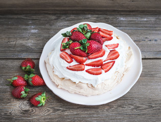 Rustic Pavlova cake with fresh strawberries and whipped cream ov