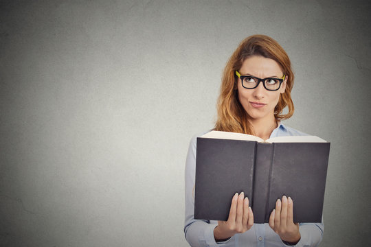 woman with glasses reading book having thought