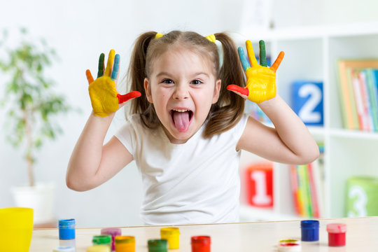 Funny kid with hands painted in colorful paint