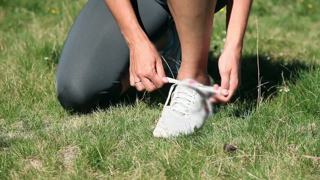 Woman tying up her shoelaces while running