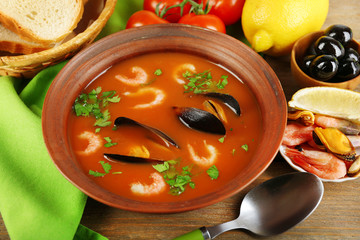 Tasty soup with shrimps, mussels, tomatoes and black olives in