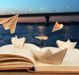 Origami boats on old book on bridge background