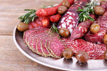 Sliced smoked sausages on metal tray on wooden table background