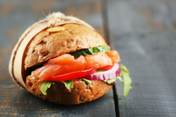 Sandwich with salmon on color wooden background