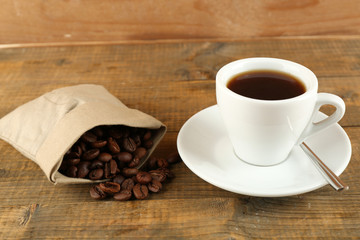 Cup of coffee with beans on rustic wooden background