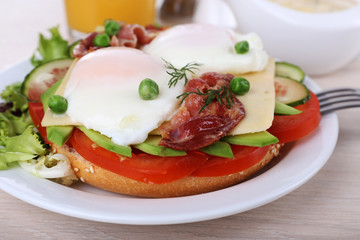 Sandwich with poached eggs, bacon and vegetables