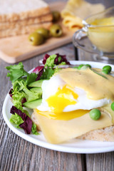 Toast with egg Benedict and avocado on plate on wooden table