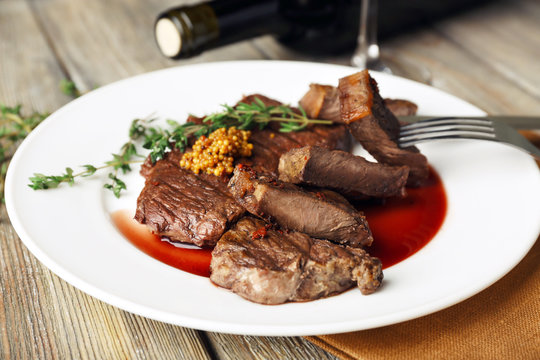 Steak on plate with bottle of wine on wooden background