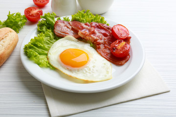 Bacon and eggs on color wooden table background