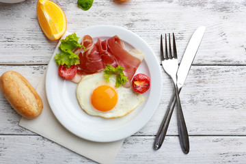 Bacon and eggs on color wooden table background.