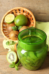 Tasty kiwi jam in glass jar on wooden background