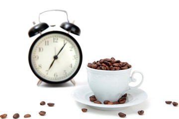 Fototapeta na wymiar The alarm clock and white cup filled by coffee beans