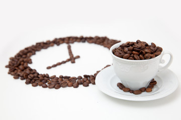 Roasted coffee beans in shape of clock and white cup