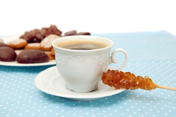 The cup of espresso with sugar stick and plate of cookies