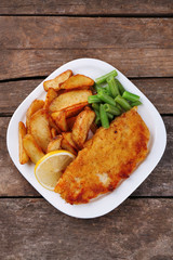 Breaded fried fish fillet and potatoes with asparagus and lemon