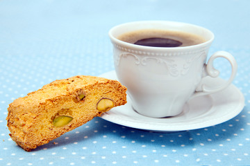 The white cup of coffee with piece of cookie on table