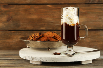Cup of coffee with cream and cookies on wooden background