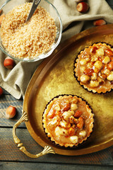 Mini cakes with nuts on napkin on wooden background