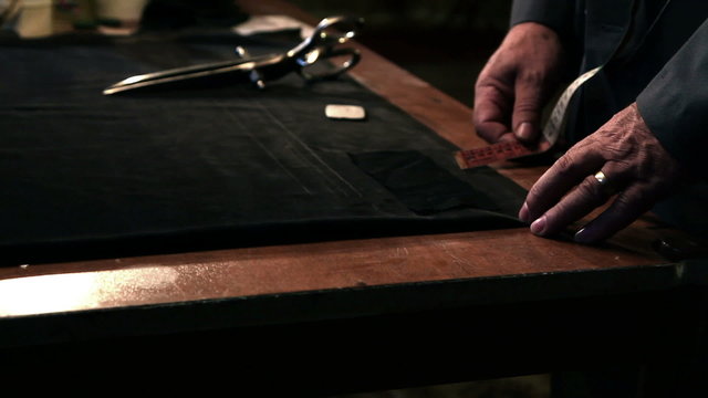 Shot of an old tailor measuring fabric