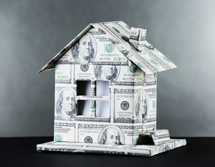 Money house on table on gray background