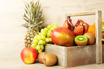 Assortment of exotic fruits in box on wooden background