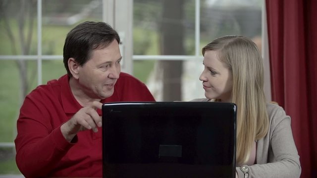 Father helps his daughter around using personal computer