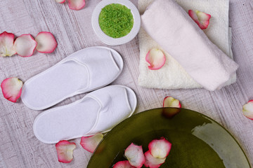 Spa bowl with water, rose petals, towel and slippers