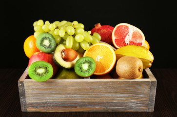 Assortment of fruits in box on black background