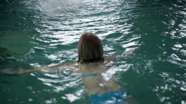 Still shot of a pretty young woman in blue bikini that swimms away from the camera