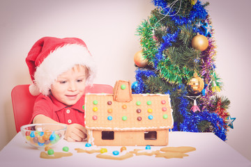 Smiling boy in Santa's hat with gingerbread house